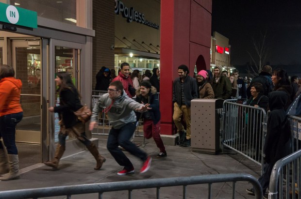Black Friday crowds line the front of a store; customers in line rush inside